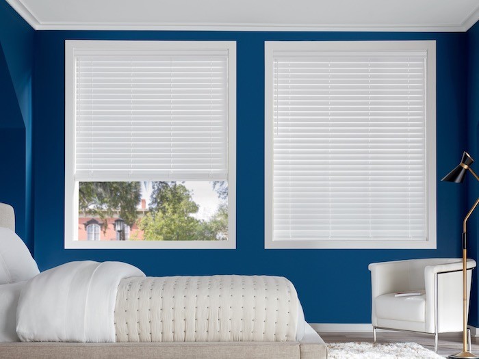 A bedroom with bright blue wall and white furniture.